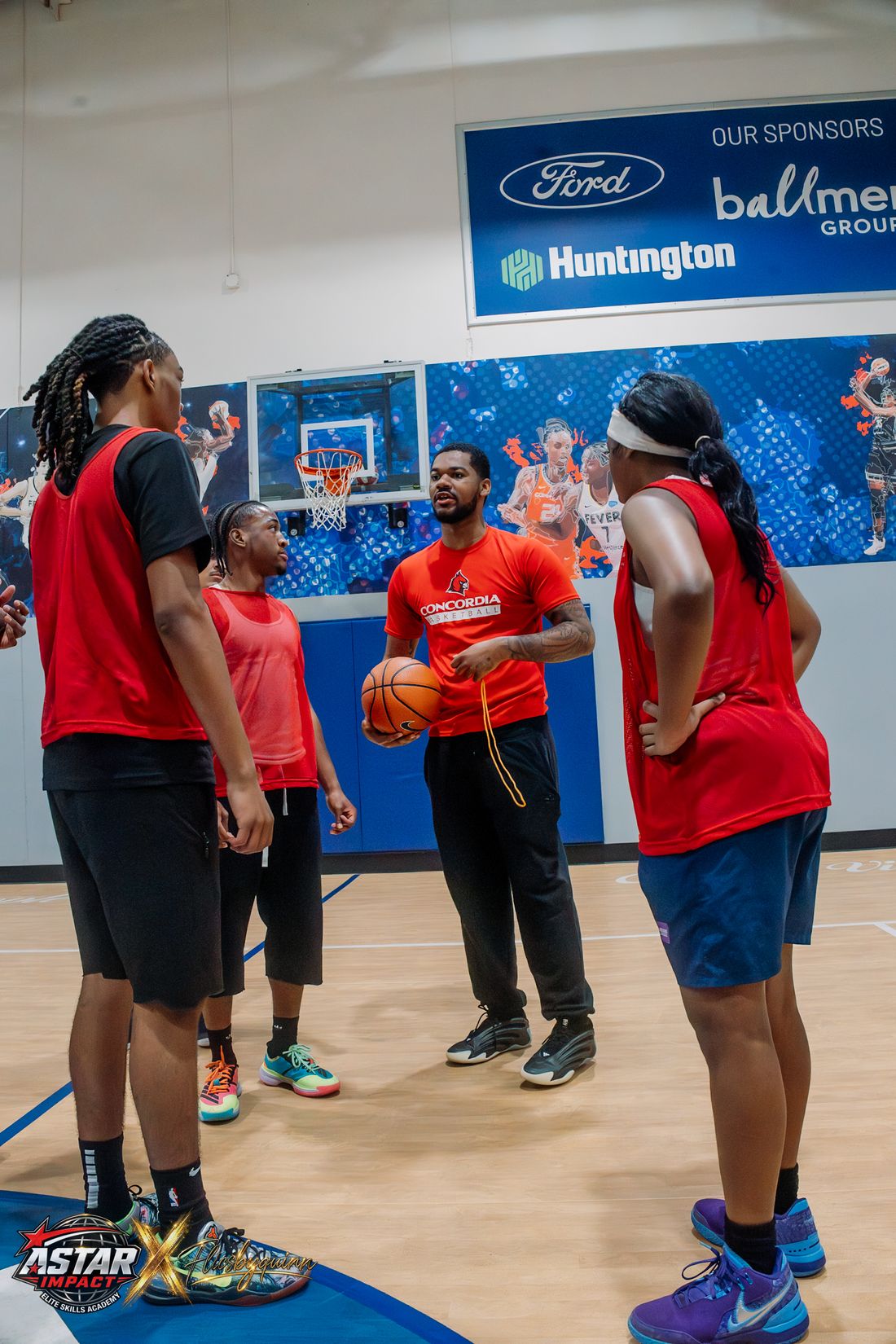 A coach holding a basketball and instructing athletes